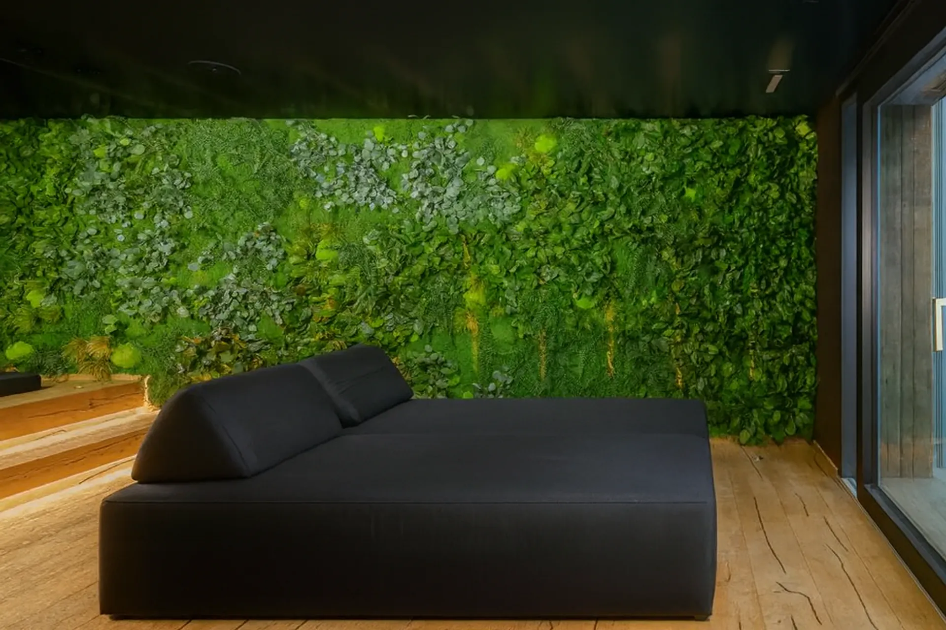 Mur en mousse « Relaxzone » avec canapé noir — Aménagement végétal mural par MOOSMOOS